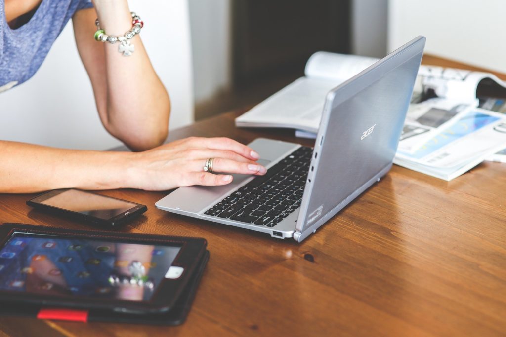 Femme qui travail sur un ordinateurs avec une tablette à côté